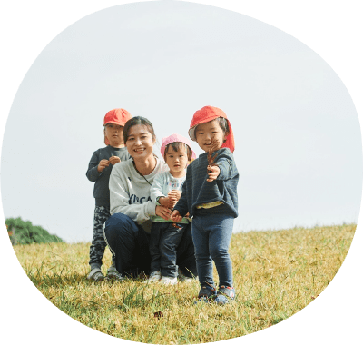 子供と先生が芝生で一緒に遊んでいる写真